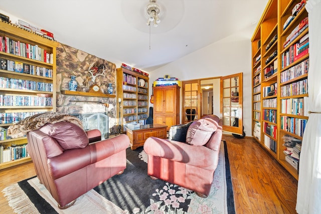 sitting room with built in features, hardwood / wood-style floors, vaulted ceiling, and ceiling fan