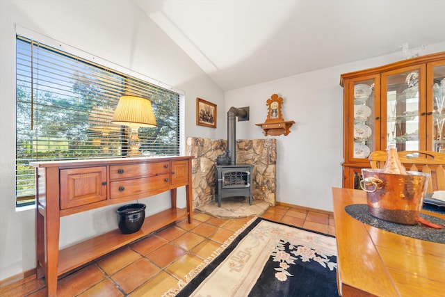 interior space featuring a wood stove, light tile patterned floors, and vaulted ceiling