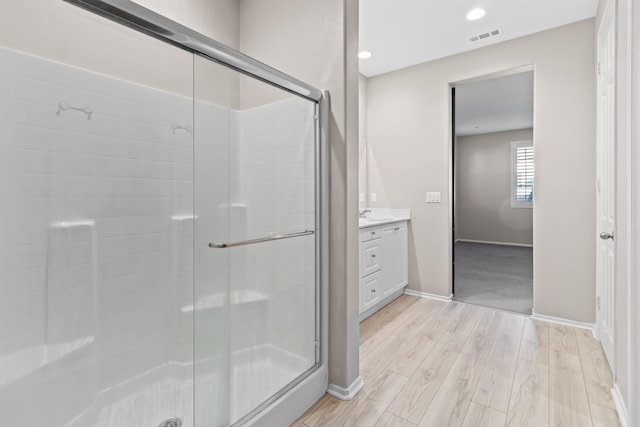 bathroom featuring a shower with shower door, vanity, and hardwood / wood-style flooring