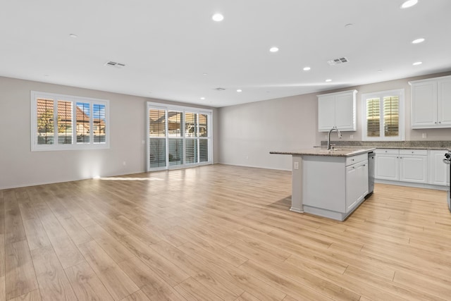 kitchen featuring white cabinets, sink, plenty of natural light, and an island with sink