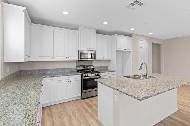 kitchen featuring white cabinets, a center island with sink, and stainless steel appliances