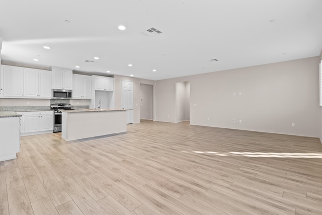 kitchen with a kitchen island, light hardwood / wood-style floors, sink, appliances with stainless steel finishes, and white cabinets