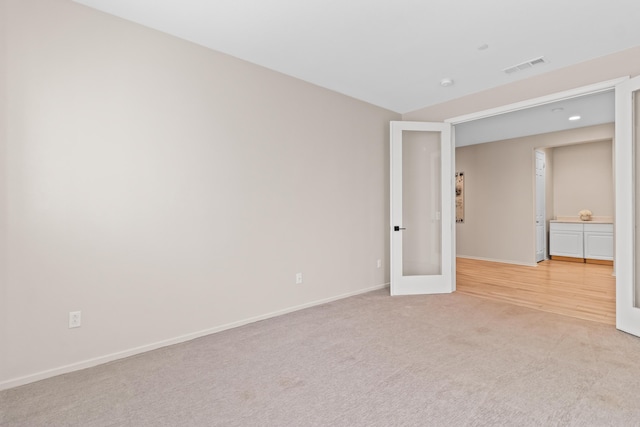 carpeted spare room featuring french doors