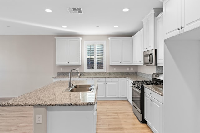 kitchen featuring light hardwood / wood-style floors, a center island with sink, stainless steel appliances, white cabinets, and sink