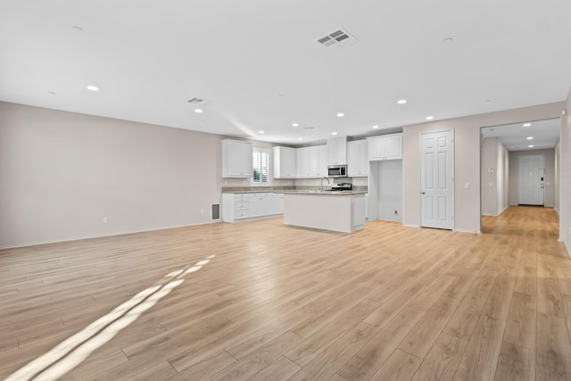 unfurnished living room with sink and light hardwood / wood-style flooring