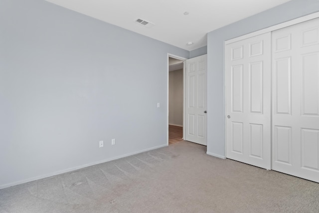 unfurnished bedroom featuring a closet and light carpet