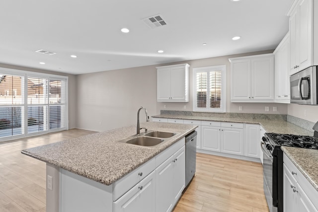 kitchen featuring stainless steel appliances, an island with sink, white cabinets, and sink