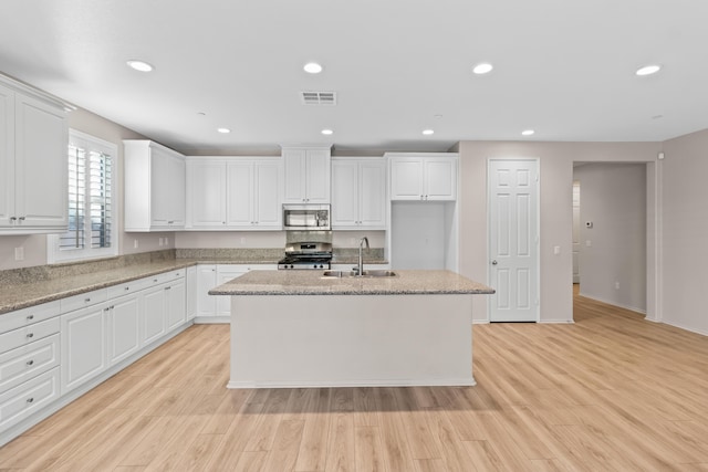 kitchen with appliances with stainless steel finishes, white cabinets, a center island with sink, and sink