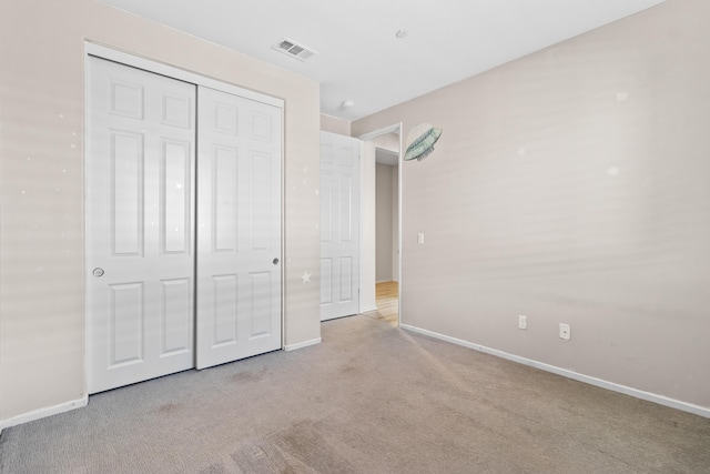 unfurnished bedroom with light colored carpet and a closet