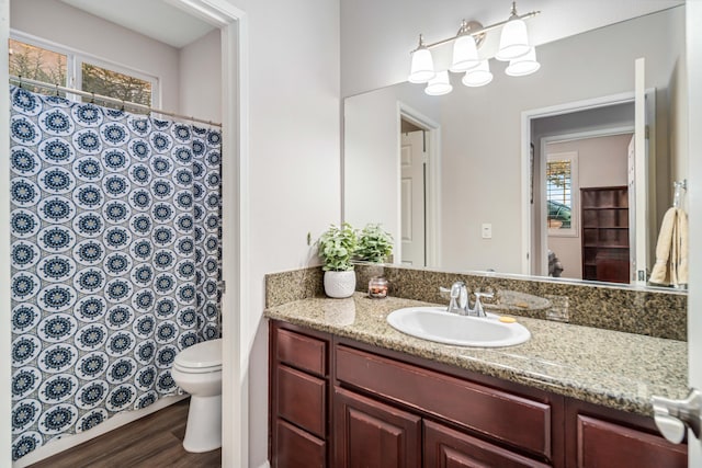 full bath with curtained shower, toilet, vanity, and a healthy amount of sunlight