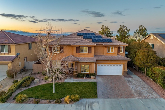 traditional home with stucco siding, a tile roof, decorative driveway, fence, and an attached garage