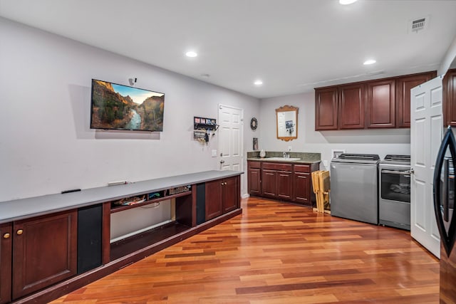 kitchen with light wood finished floors, recessed lighting, range, washer and dryer, and a sink