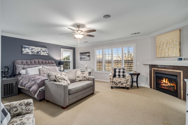 carpeted bedroom with visible vents, crown molding, baseboards, ceiling fan, and a tile fireplace