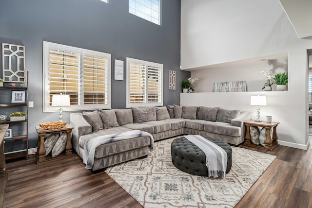 living area with a high ceiling, baseboards, and wood finished floors