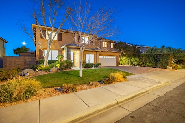 view of front of home with stucco siding, a front lawn, driveway, fence, and an attached garage