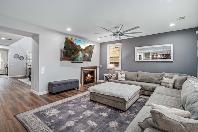 living room featuring visible vents, baseboards, recessed lighting, a ceiling fan, and dark wood-style flooring