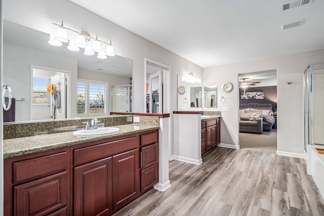 bathroom featuring a shower stall, wood finished floors, visible vents, and a sink