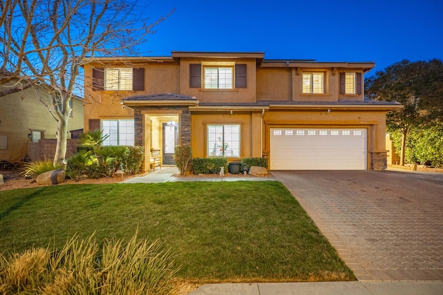 prairie-style house with stucco siding, decorative driveway, stone siding, a front yard, and an attached garage