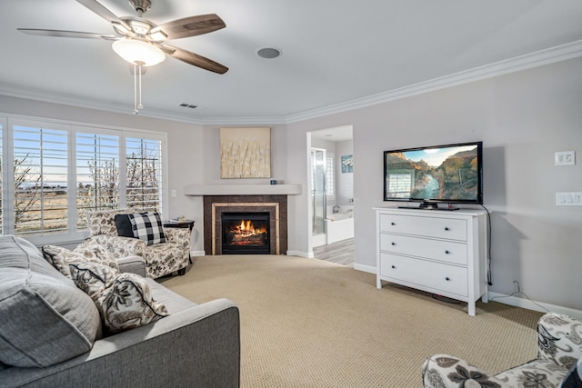 carpeted living area featuring a tiled fireplace, baseboards, visible vents, and ornamental molding