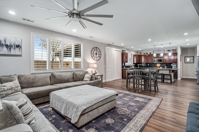 living area with dark wood-type flooring, recessed lighting, a ceiling fan, and visible vents