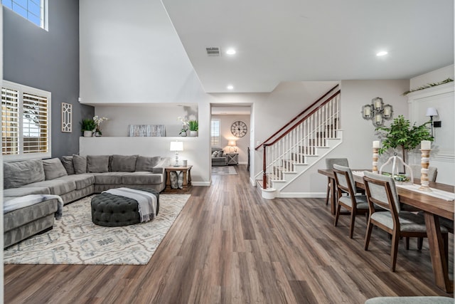 living area with recessed lighting, visible vents, wood finished floors, and stairs