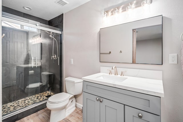 full bath with visible vents, toilet, a stall shower, wood finished floors, and vanity