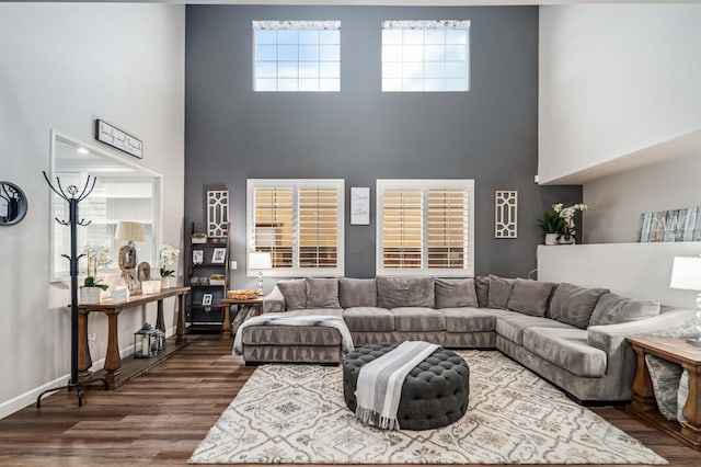 living area featuring a high ceiling, baseboards, and dark wood-style flooring