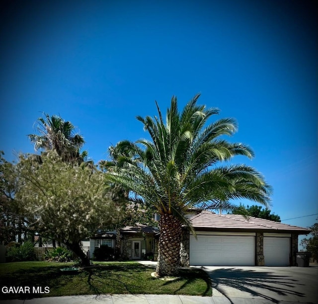 6001 Brougham St, Lancaster, CA 93536 - obstructed view of property featuring stone siding, a garage, driveway, and a front lawn