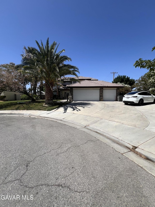 6001 Brougham St, Lancaster, CA 93536 - obstructed view of property with concrete driveway, solar panels, stone siding, and a garage