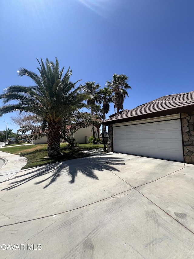 6001 Brougham St, Lancaster, CA 93536 - view of front of house featuring concrete driveway, an attached garage, stone siding, and a tiled roof