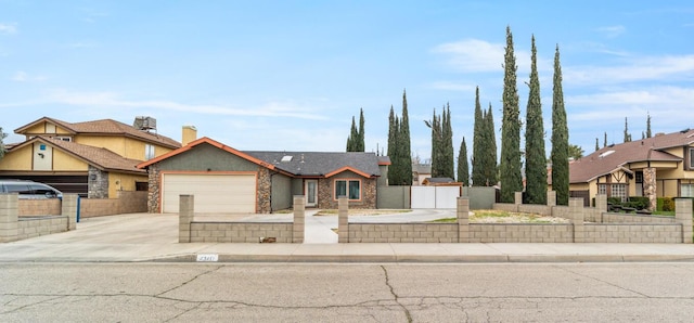 view of front of home with stone siding, an attached garage, driveway, and a fenced front yard