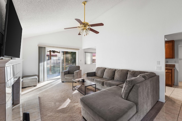 living room with ceiling fan, vaulted ceiling, a textured ceiling, and light tile patterned floors