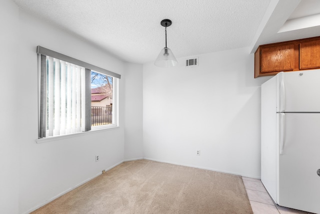 unfurnished dining area featuring light tile patterned floors and a textured ceiling