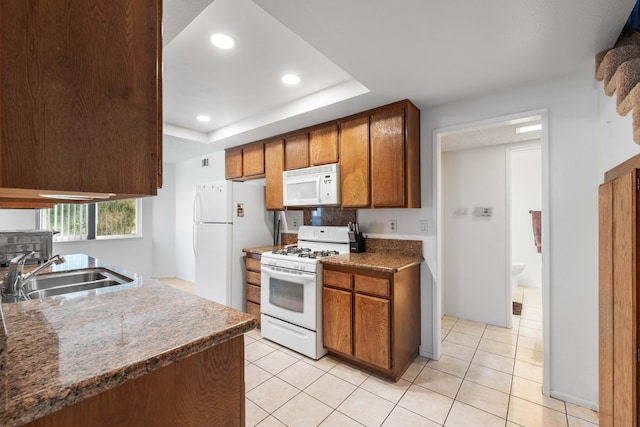 kitchen featuring sink, white appliances, light tile patterned floors, and a raised ceiling