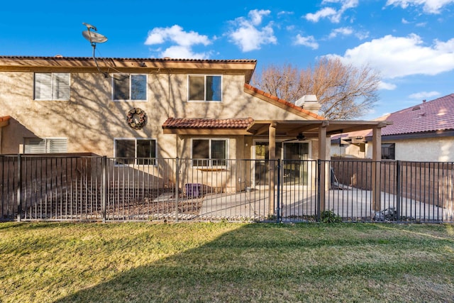 back of property with a yard, ceiling fan, and a patio area