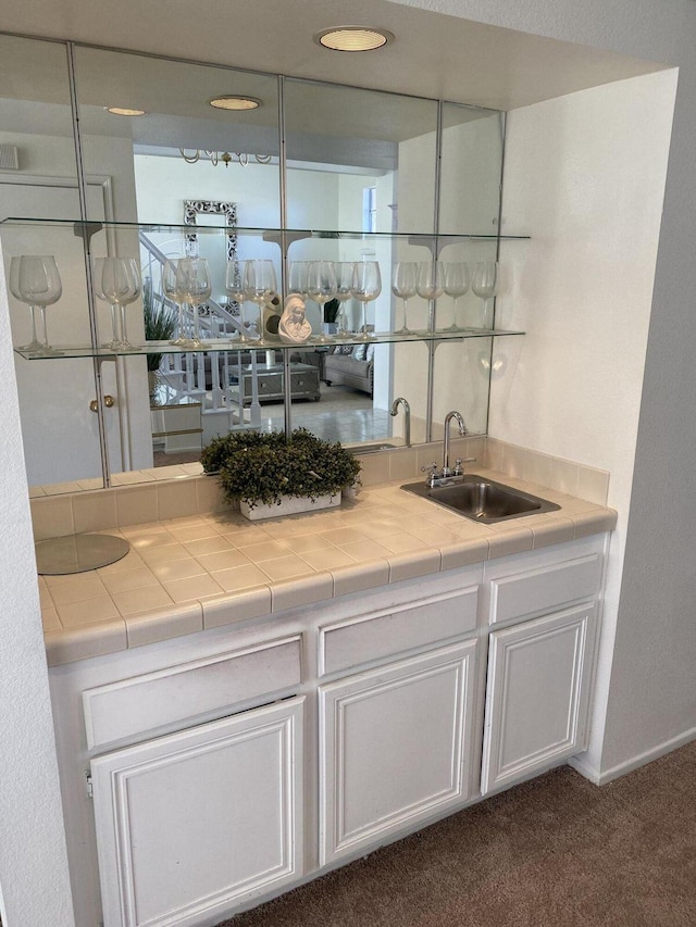 bar featuring tile counters, dark carpet, white cabinetry, and sink