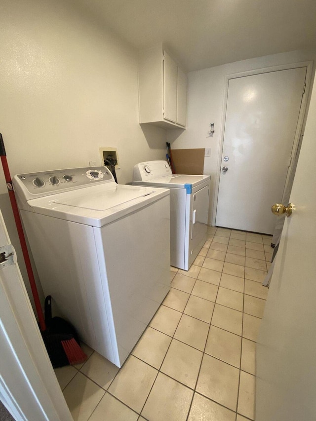 laundry area with light tile patterned flooring, cabinets, and independent washer and dryer