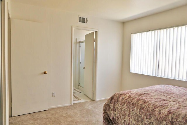 bedroom with ensuite bathroom, multiple windows, and light colored carpet