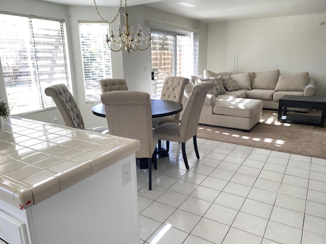 tiled dining room featuring plenty of natural light and an inviting chandelier