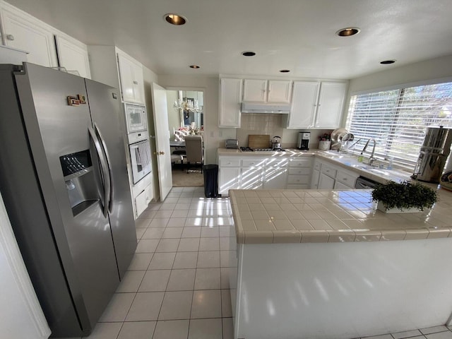 kitchen featuring tile countertops, white cabinetry, stainless steel appliances, and light tile patterned floors