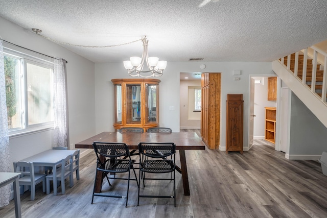 dining area featuring an inviting chandelier, dark wood-type flooring, and a textured ceiling