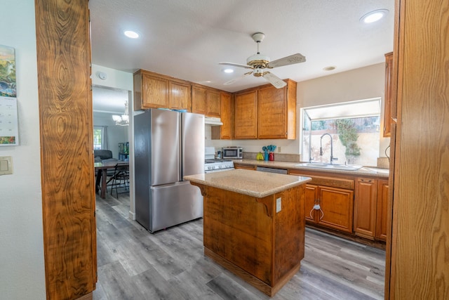 kitchen with a healthy amount of sunlight, a kitchen island, sink, and stainless steel refrigerator