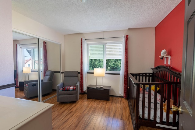 bedroom featuring a closet, hardwood / wood-style floors, multiple windows, and a textured ceiling