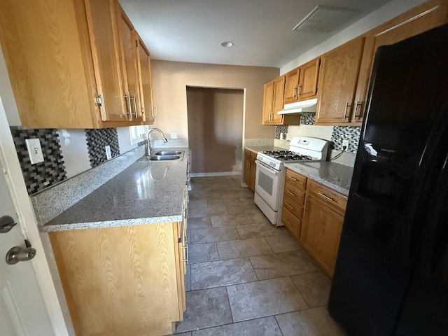 kitchen with under cabinet range hood, white gas range oven, decorative backsplash, black refrigerator with ice dispenser, and a sink