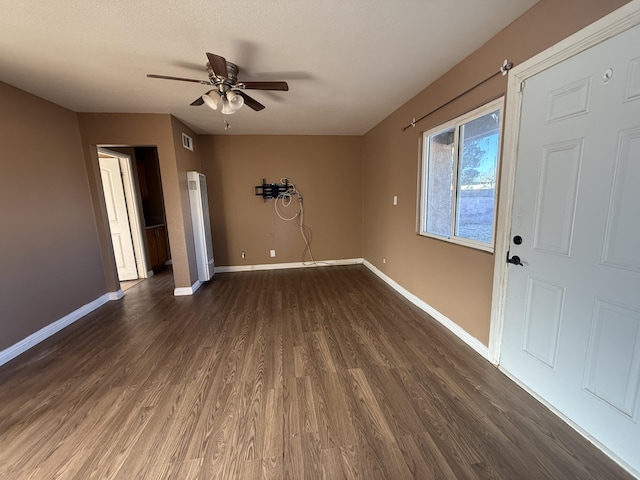 interior space with a ceiling fan, visible vents, baseboards, arched walkways, and dark wood-type flooring