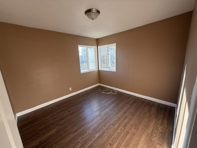 empty room featuring baseboards and dark wood-style flooring