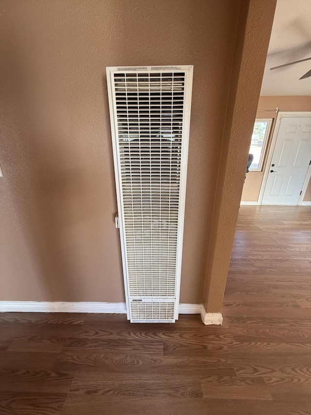 room details with wood finished floors, a heating unit, baseboards, ceiling fan, and a textured wall