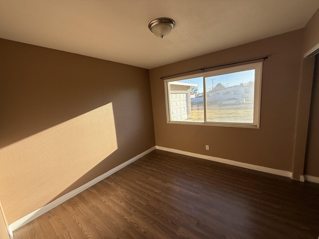 empty room featuring dark wood finished floors and baseboards