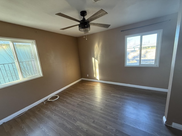 empty room featuring baseboards, dark wood-type flooring, and a ceiling fan