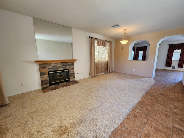 unfurnished living room featuring a fireplace, visible vents, and carpet flooring